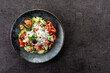 Traditional Bulgarian shopska salad with tomato,cucumber and bulgarian sirene cheese on black background.Top view. Copy space