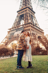 A couple kissing in front of the Eiffel Tower in Paris. Romantic trip, honeymoon in Europe. France city of love