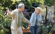 Happy loving senior couple holding hands and walking in their garden on warm spring day, enjoying time together