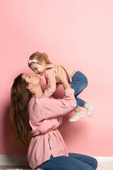 portrait of young woman and little girl, mother and daughter isolated on pink studio background. mot