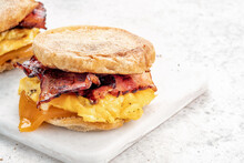 English Muffin, Egg, Ham, And Cheese Breakfast Sandwich On A Cutting Board