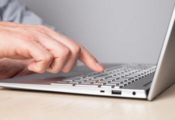 Poster - Man hand closeup pressing enter key. Man sitting at table and working on laptop. High quality photo