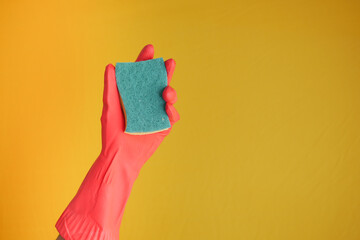 Sticker -  hand in rubber gloves holding sponge against yellow 