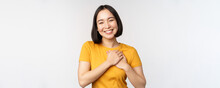 Romantic Asian Girfriend, Holding Hands On Heart, Smiling With Care And Tenderness, Standing In Yellow Tshirt Over White Background