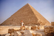 Man tourist with hat and bag walks background of pyramids in Giza Cairo Egypt, sun light travel