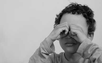 Wall Mural - boy crying with hand over face crying alone and all by himself with white background stock photo