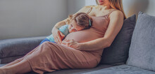 Little Baby Girl Relaxing On Mom's Pregnant Belly - Pregnant Mother With A Toddler - Family Concept