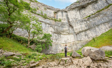 Yorkshire Dales National Park, Yorkshire, UK - March 14, 2022; A Person Looks Up At Malham Cove, Yorkshire Dales National Park, Yorkshire, UK