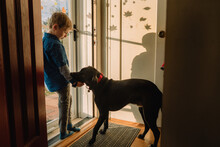 A Little Boy And His Dog Stand By The Front Door.