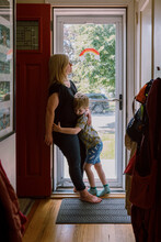 A Mother Hugs Her Son In A Doorway.