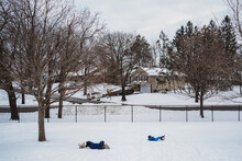 Two Children Roll Down A Snowy Hill.