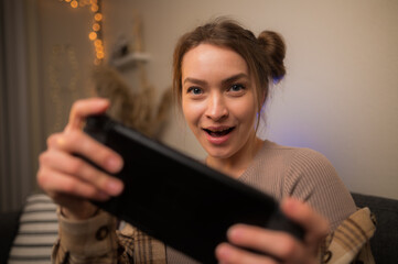 Wall Mural - Player plays on portable console, young girl with smile plays on portable console.Concept of cyberprot, entertainment for children, computer games