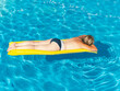 © marcelinopozo - Caucasian mature woman lying on yellow inflatable mattress sunbathing a swimming pool