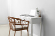 © Pixel-Shot - Modern workplace with laptop and wicker chair near light wall