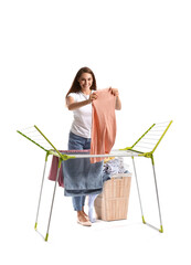 Wall Mural - Beautiful woman hanging clean laundry on dryer against white background