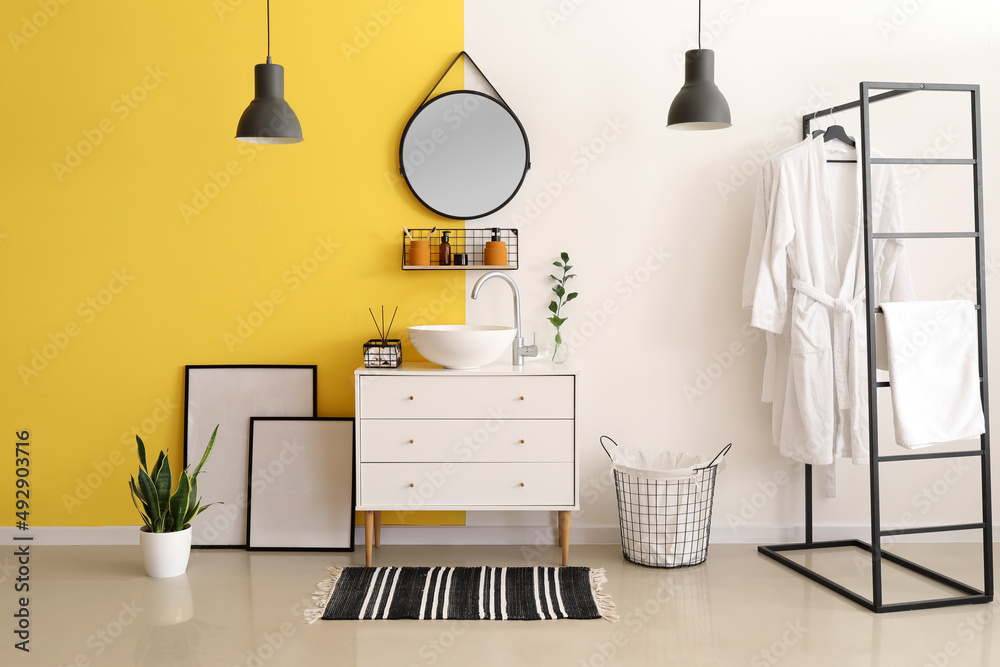 Interior of stylish bathroom with drawers, sink and mirror