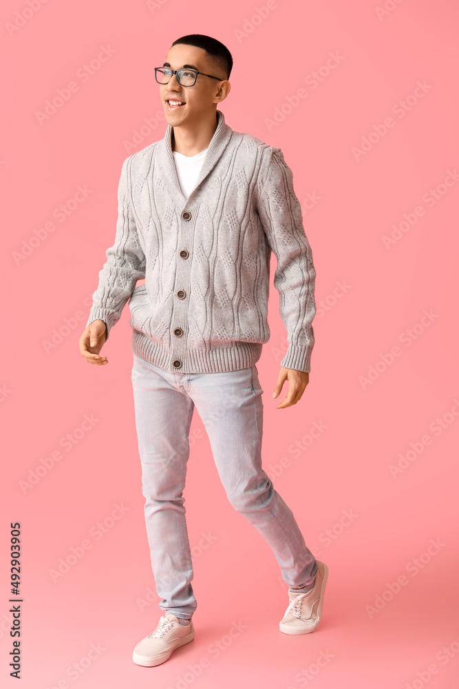 Handsome young Asian man in knitted sweater on pink background