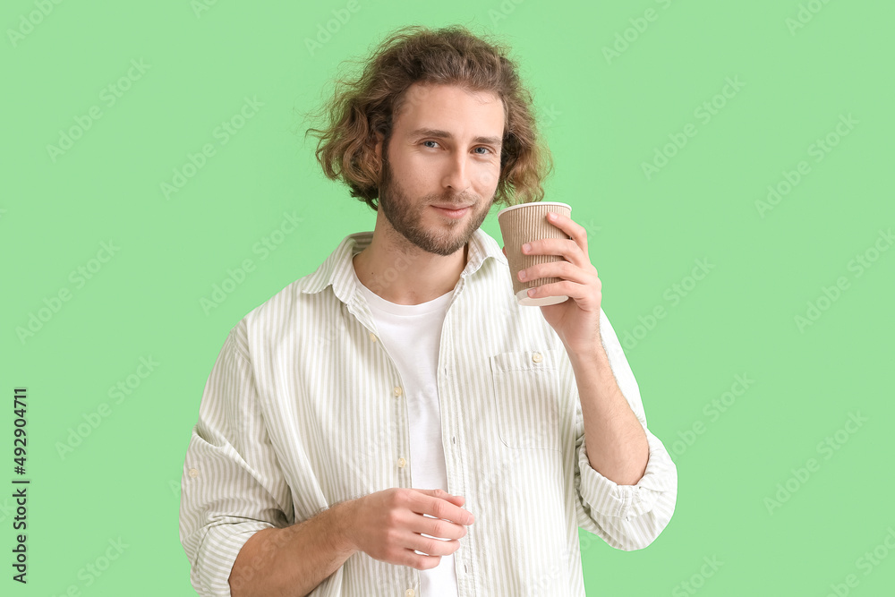 Handsome man with cup of coffee on green background