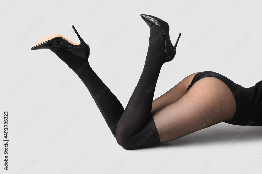 Beautiful young woman in black tights on light background