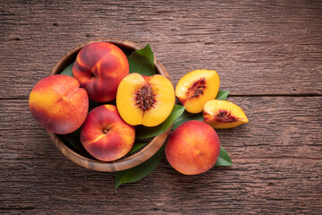 Wall Mural - Sweet Yellow Peach with slice in wooden basket, Fresh Yellow Peach fruit in wooden bowl on wooden background.