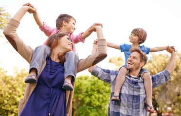 Poster - Enjoying some family fun. Shot of a young mother and father carrying their sons on their shoulders.