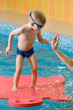 © ninelutsk - Toddler child learning to dive in indoor swimming pool with teacher. Standing on side, balancing and general physical activity for kids in water, early development. Boy kid instructed