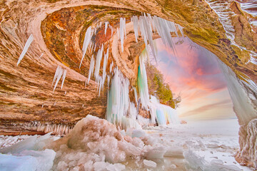 Stunning ice cave entrance during sunrise on Lake Michigan with icicles and broken ice