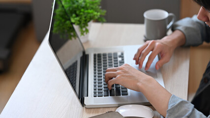 Wall Mural - Young man working online, checking email in morning on laptop computer at home.