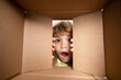 © Volodymyr - Kid opening package. Child boy age 6 year opening a carton box and looking inside, unpacking concept, surprise unboxing.
