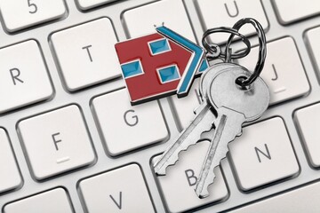 Sticker - House key and home symbol shaped keychain on laptop keyboard online internet property search concepts