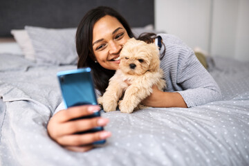 Wall Mural - Selfies with my floofy. Shot of a young woman taking selfies with her dog at home.