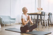 © yurolaitsalbert - elderly woman meditating sitting on the floor in her living room.