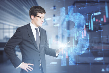 Poster - Attractive young caucasian businessman holding tablet with creative glowing bitcoin grid forex chart hologram on blurry office interior background. Cryptocurrency and growth concept. Double exposure.