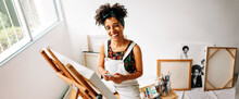Cheerful Painter Holding A Smartphone In Her Art Studio