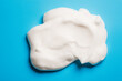 White mousse soap or shaving cream or facial cleanser product on blue background copy space.	