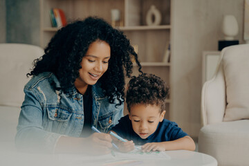 Pretty afro american mom and little boy drawing with colored felt tip pens