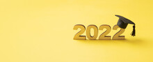 Graduated Hat Or Cap With Wooden Number 2022 On A Yellow Glitter Background. Class 2022 Banner Format
