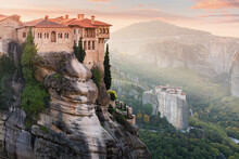 Monastery Of Varlaam And Saint Barbara Rousanos Building On Top Of A Sandstone Rock With Ray Of Light At Sunrise. Must-visit Iconic Travel And Pilgrimage Destinations Of The World