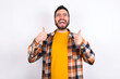 © Jihan - Optimistic young caucasian man wearing plaid shirt over white background showing thumbs up with positive emotions. Quality and recommendation concept.