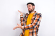 young caucasian man wearing plaid shirt over white background pointing aside with both hands showing something strange and saying: I don't know what is this. Advertisement concept.