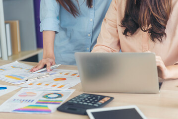 Sticker - Two businesswomen team meeting using laptop at company office desk. Two young Female freelance reading financial graph charts Planning analyzing marketing data. Asian people team working office firm.