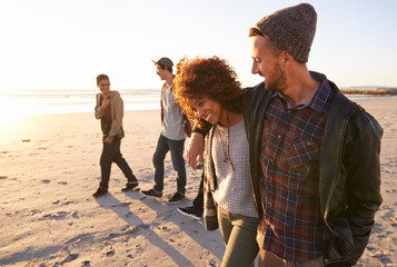 Wall Mural - Live, Laugh, Love. Shot of a group of friends walking along a beach at sunset.