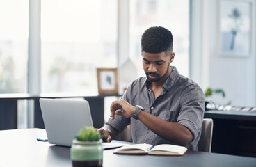 Canvas Print - Good time management allows you to accomplish more. Shot of a young businessman checking the time while working on a laptop in an office.