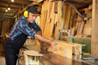 © bondvit - Senior carpenter in uniform works on a woodworking machine at the carpentry manufacturing