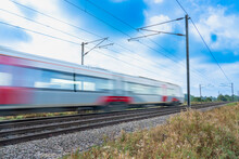 Close Up Of A Train With Overhead Electrification Speeding Through English Countryside With Motion Blur