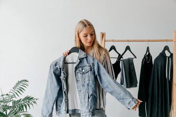 Young woman in the closet in the room showing her black Friday purchase, denim jacket