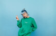 © bodnarphoto - Hipster girl in casual clothes poses for the camera on a blue background and shows a gesture of peace
