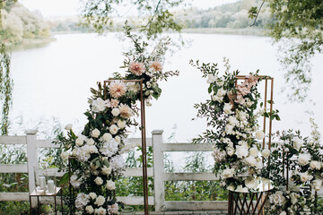 Wall Mural - Wedding arch with fresh flowers of roses by the lake in the park