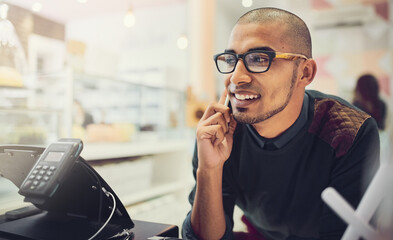 Aufkleber - Coffee is his calling. Shot of a young man talking on his cellphone in a cafe.