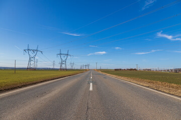 high voltage poles for electricity distribution in the countryside. in the background is a blue sky 